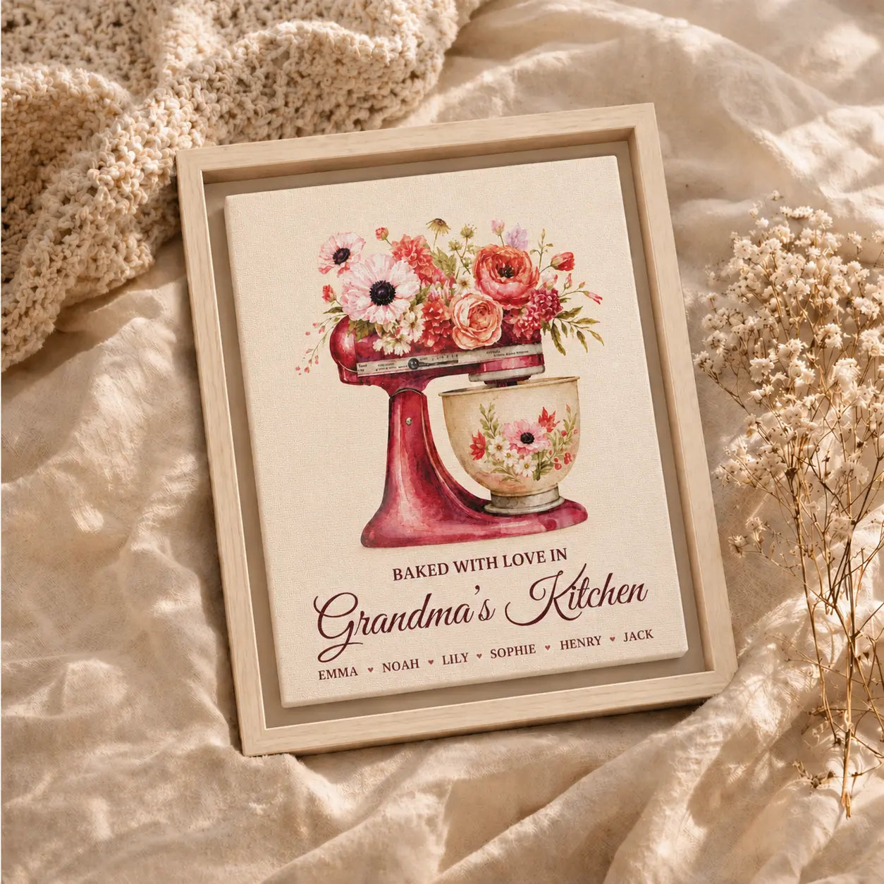 Framed artwork of a mixer with flowers and 'Baked with Love in Grandma's Kitchen' text on a soft fabric background.