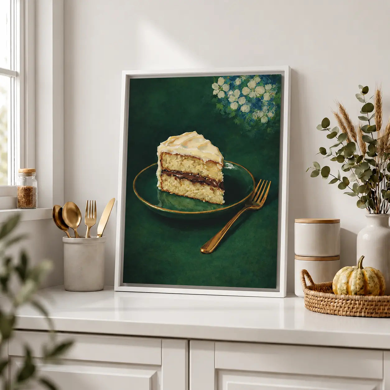 Framed artwork of a slice of cake on a plate with flowers, displayed on a kitchen counter.