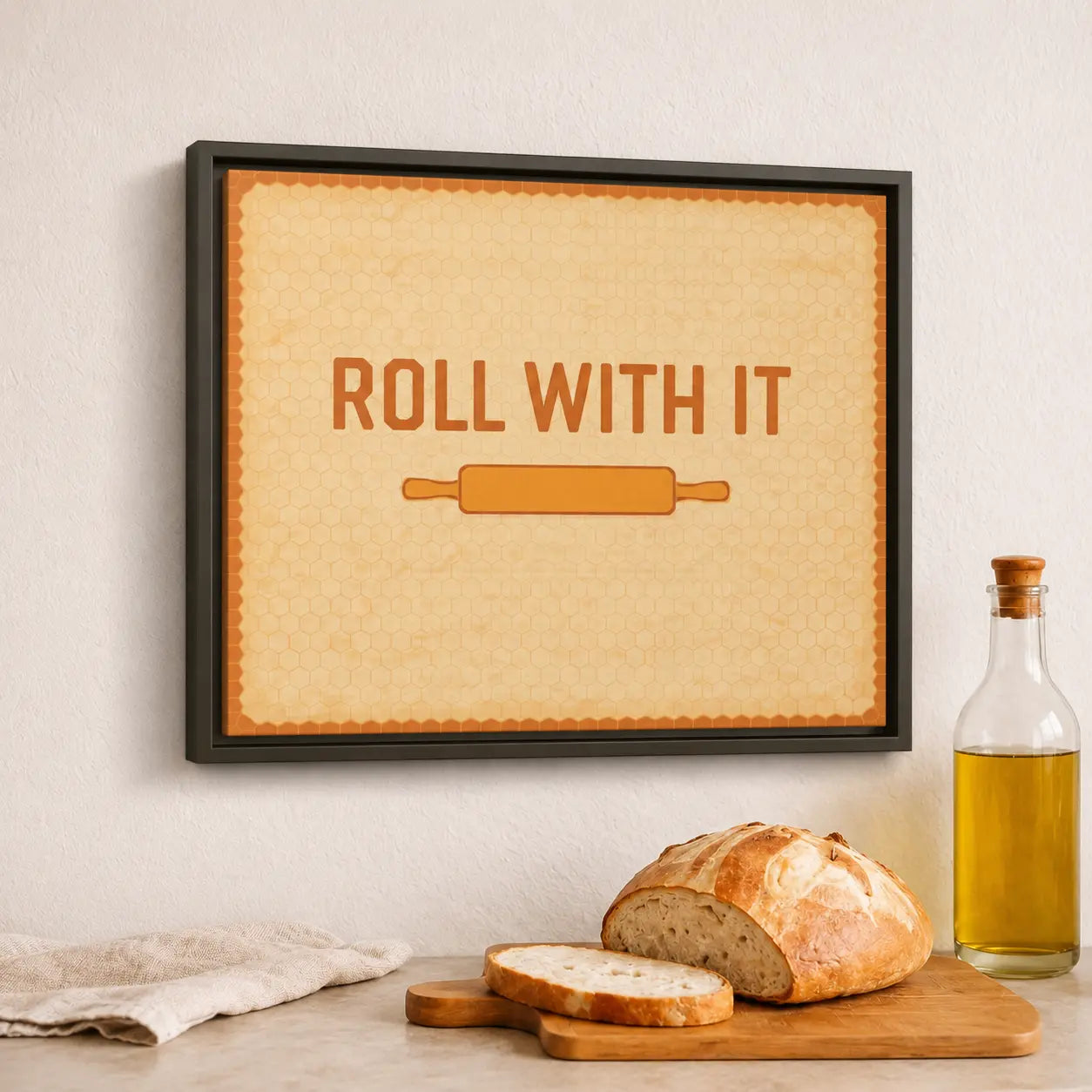 Framed kitchen wall art canvas with 'Roll with It' text and a rolling pin graphic above bread and olive oil on a table.